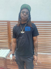 a man with dreadlocks wearing a black t - shirt and sunglasses